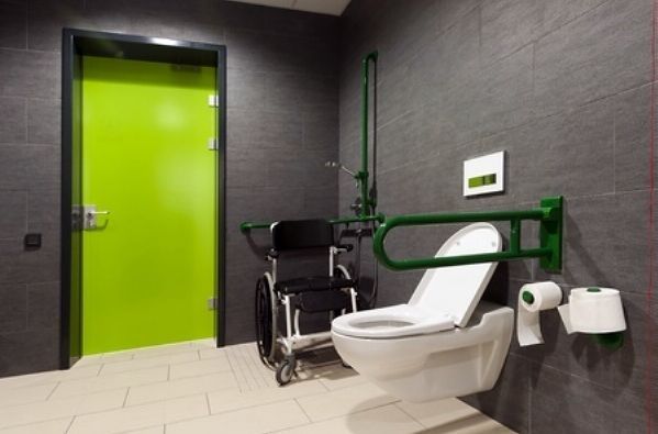 Een gehandicaptenbadkamer met toilet en rolstoel.