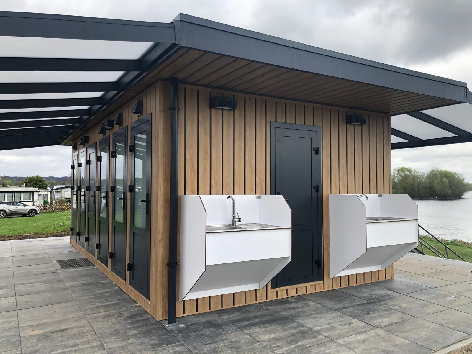 Een klein houten gebouw met twee wasbakken ervoor.