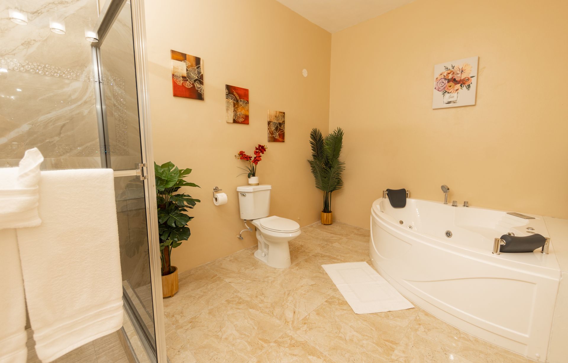 Bathroom with a shower, jacuzzi tub, toilet, and decorative plants. Light beige walls and tile floor.