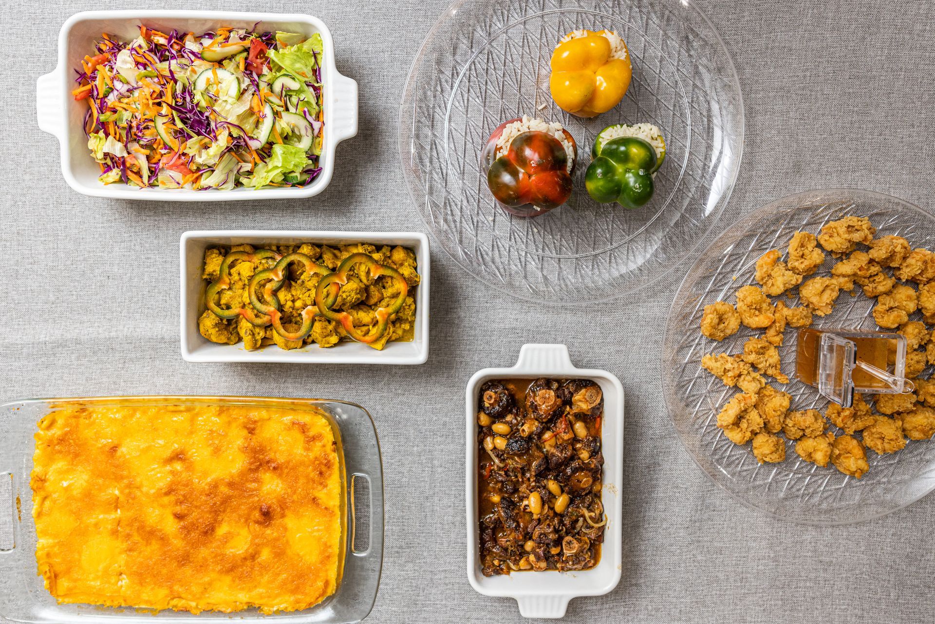 Overhead shot of various dishes: salad, peppers, pasta, meatballs, fried food, and casserole.