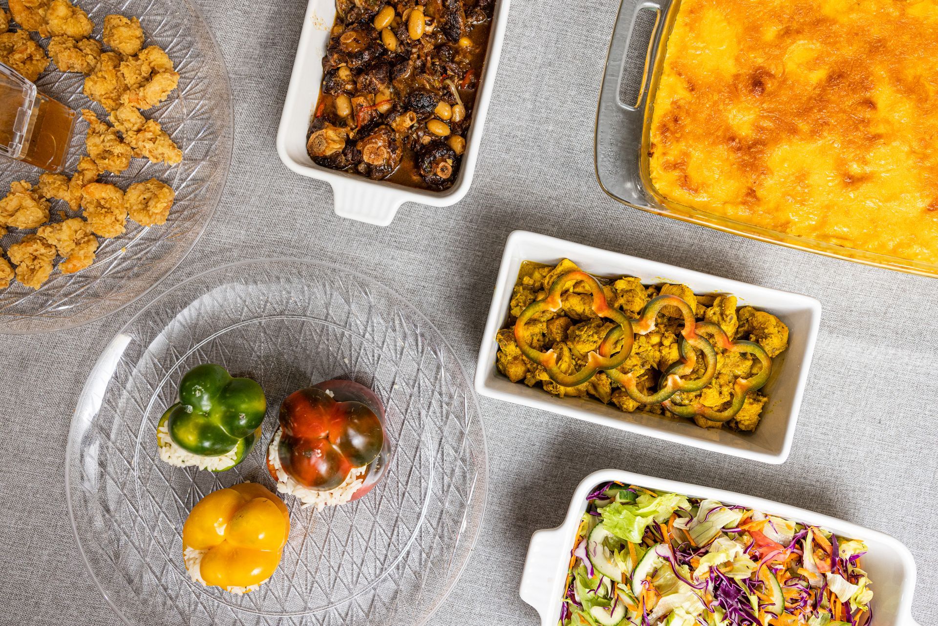 Overhead view of a buffet spread with various dishes in white serving dishes on a gray surface.