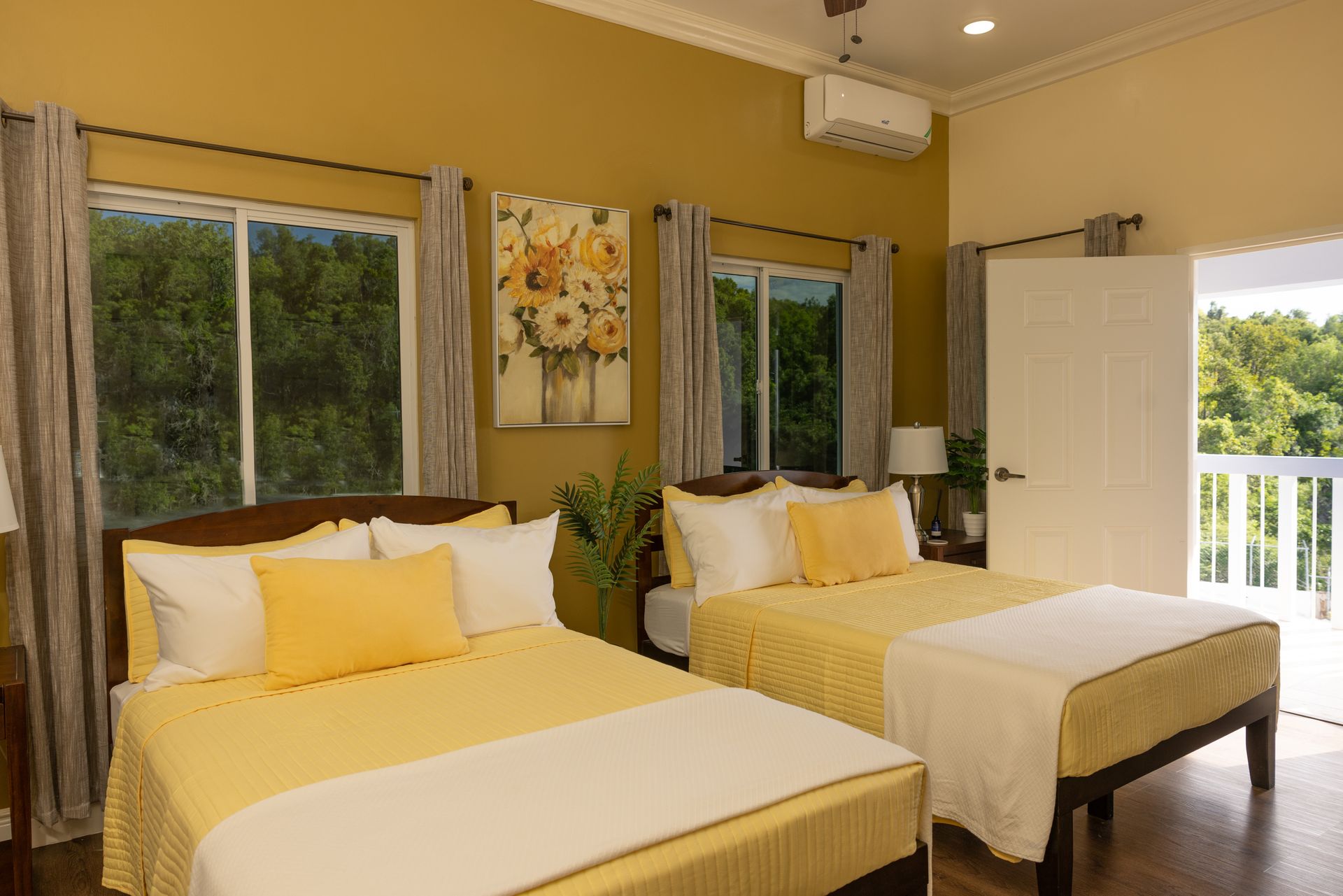 Yellow bedroom with two beds, large windows, and a door to a balcony.