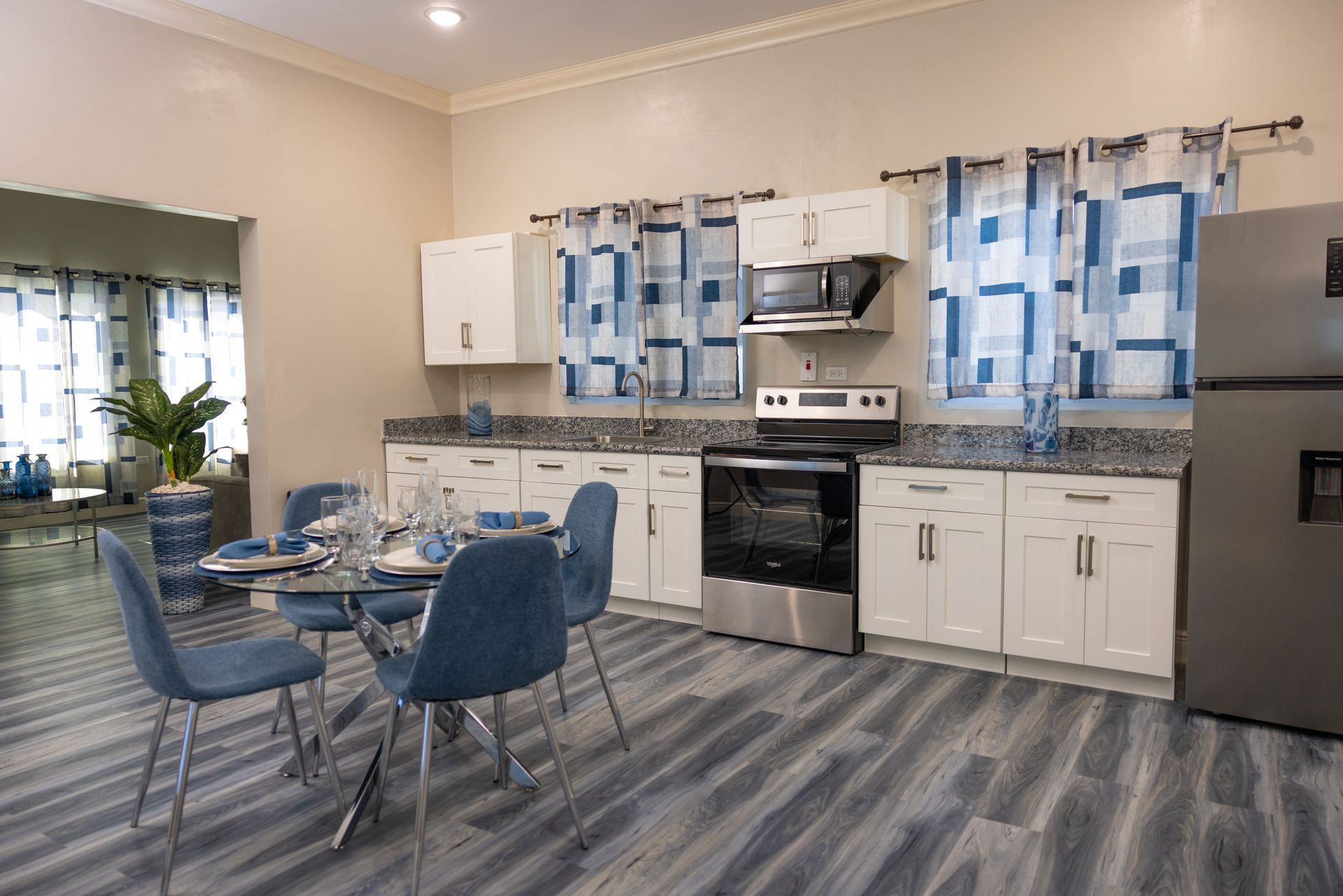 Kitchen with white cabinets, blue accents, stainless steel appliances, and a dining table.
