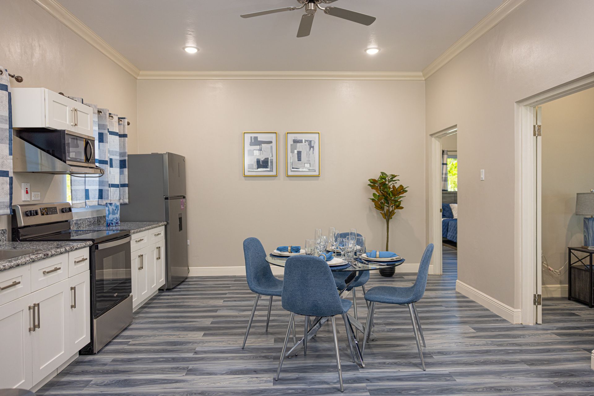 Kitchen and dining area with gray and white cabinets, blue chairs, and wood-look flooring.