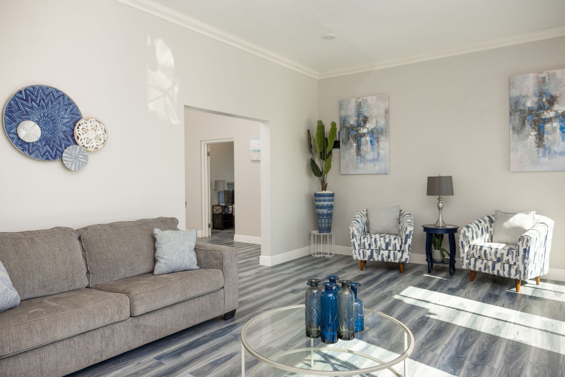 Living room with gray sofa, patterned armchairs, blue decor, and a tall cactus.