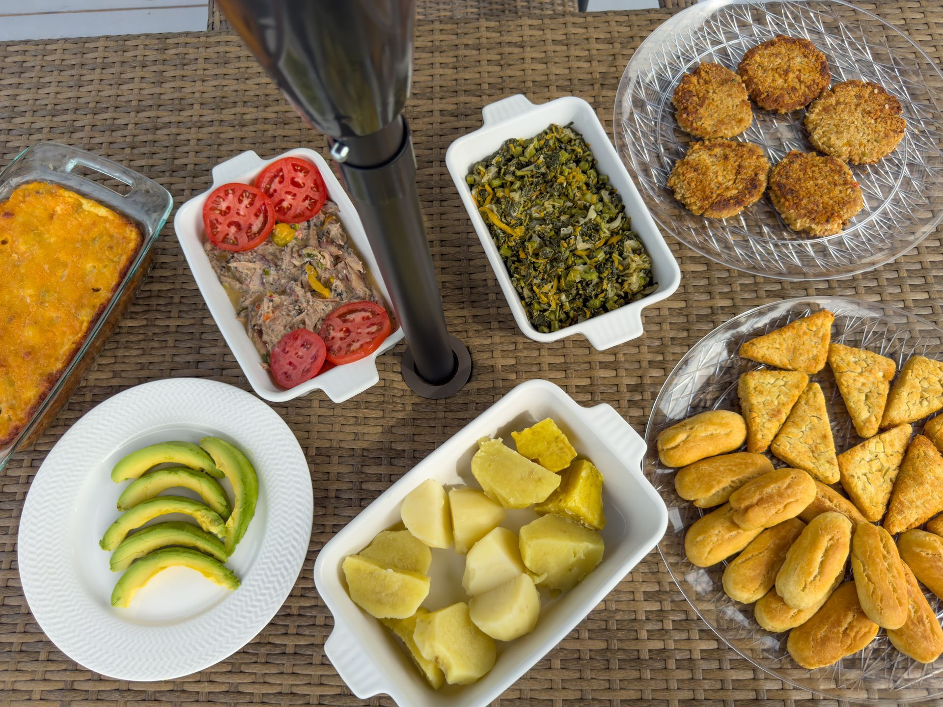 Overhead shot of various dishes: casserole, meat with tomatoes, spinach, avocado, potatoes, and fried sides.