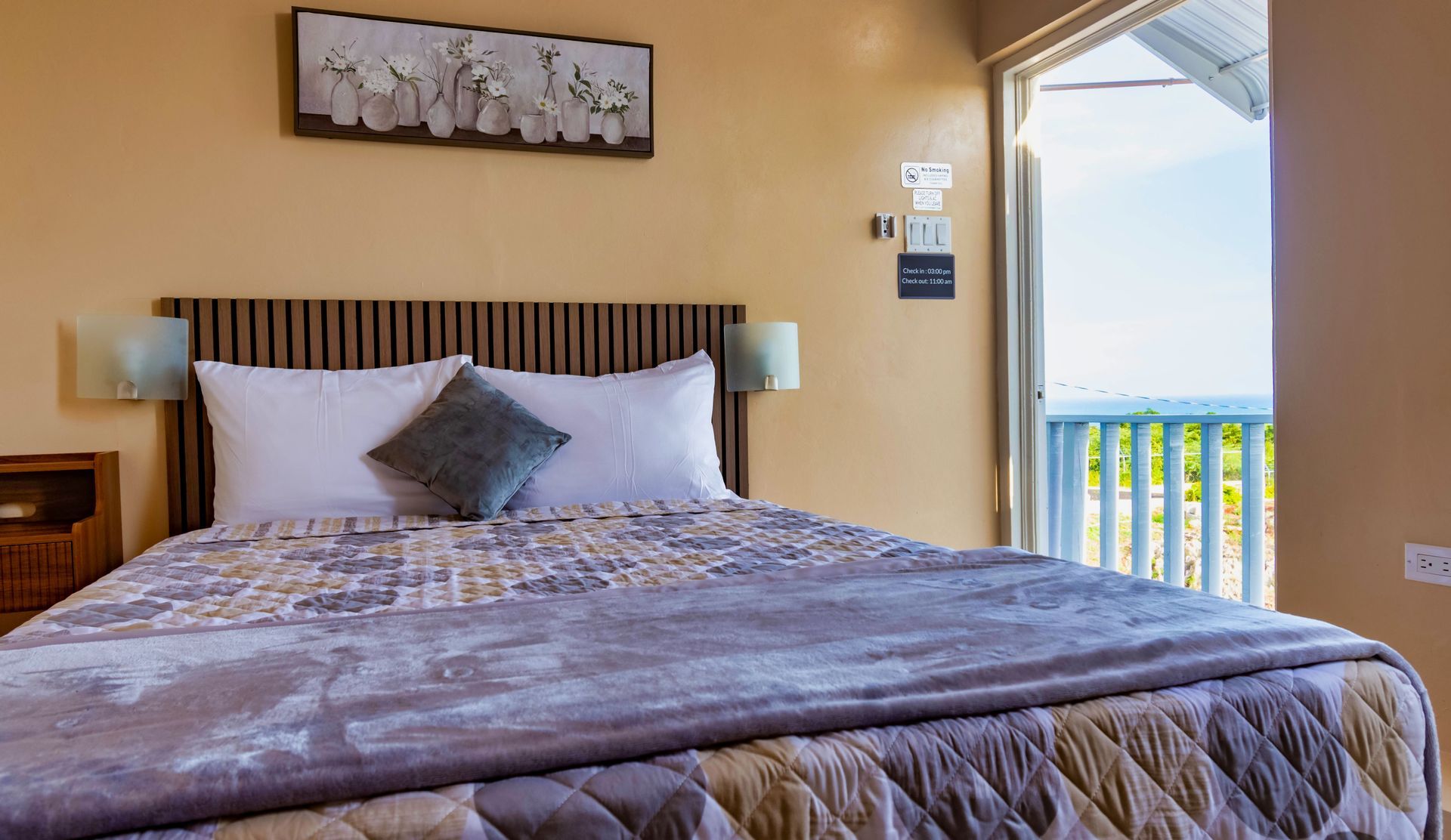 Bedroom with bed, headboard, balcony access, and artwork.