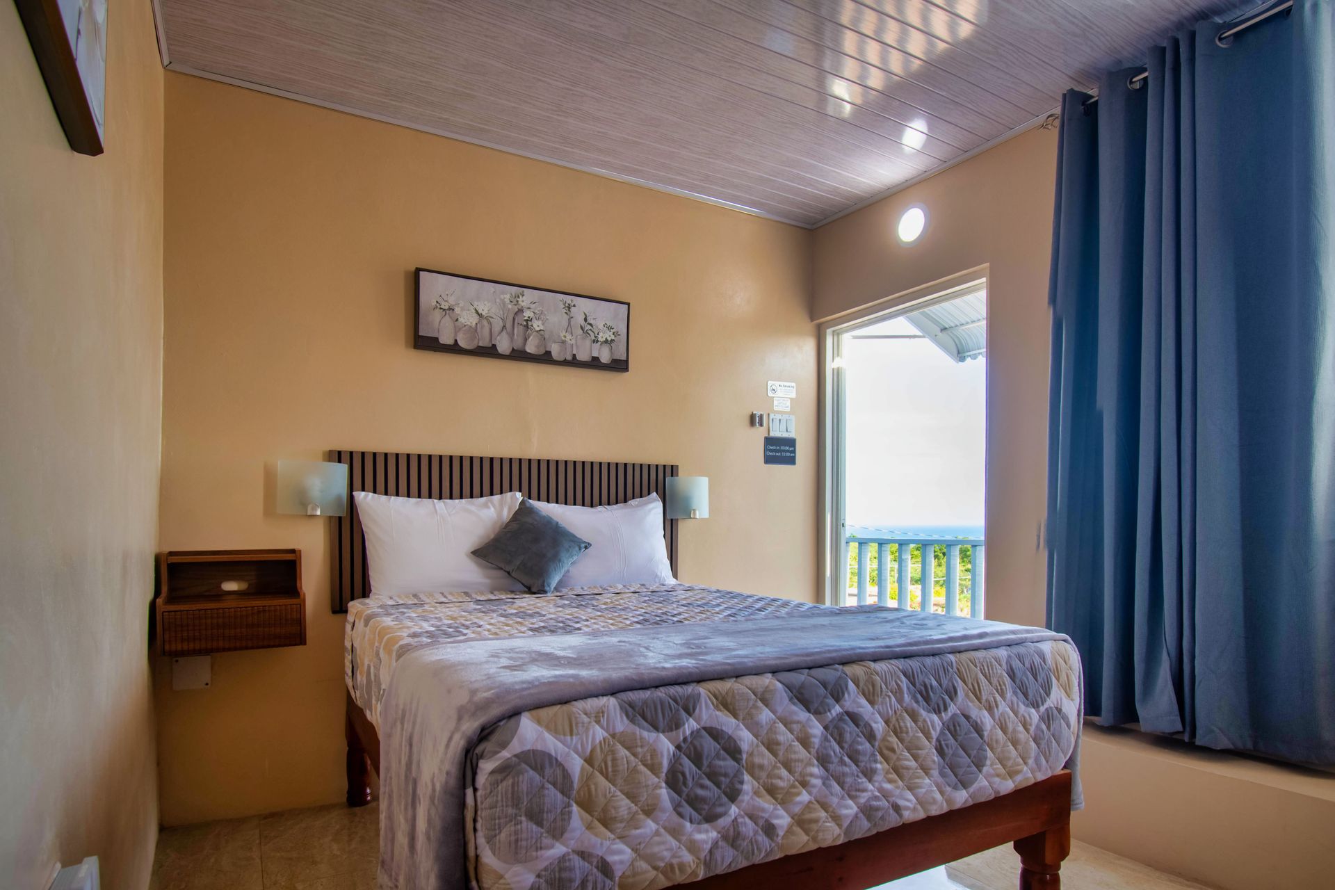 Bedroom with bed, blue curtains, and small nightstand; tan walls.