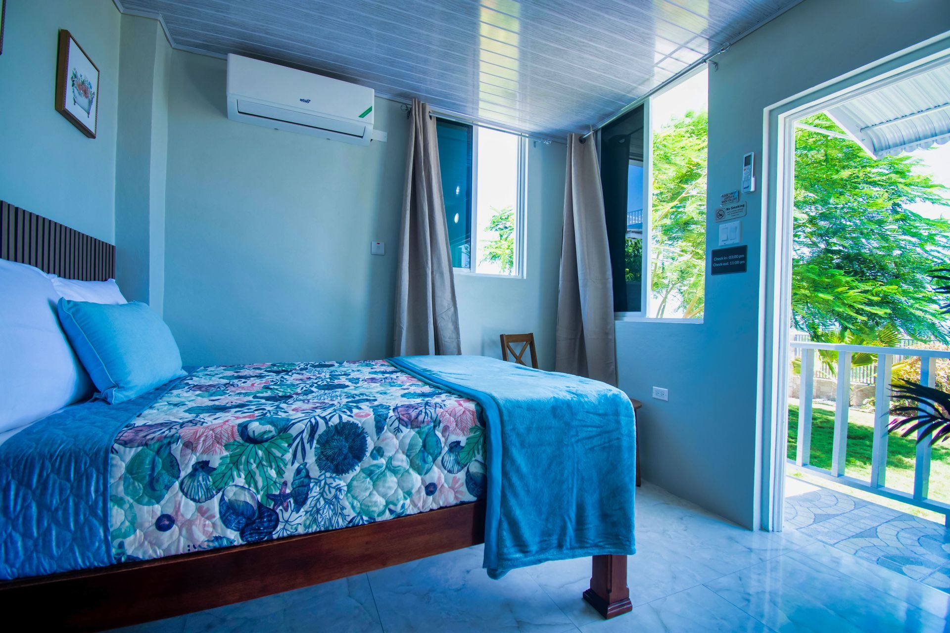 Bedroom with bed, blue accents, open door to a balcony, and air conditioner.