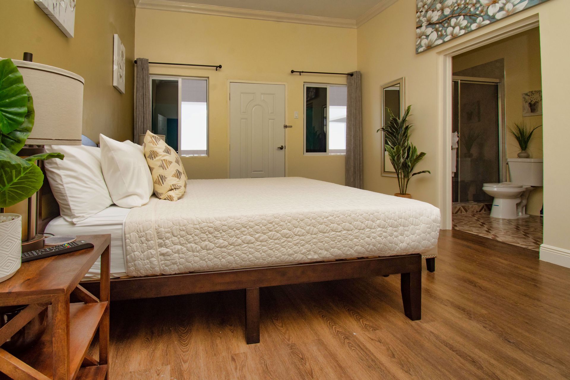 Bedroom with bed, nightstand, windows, and an open doorway to a bathroom.