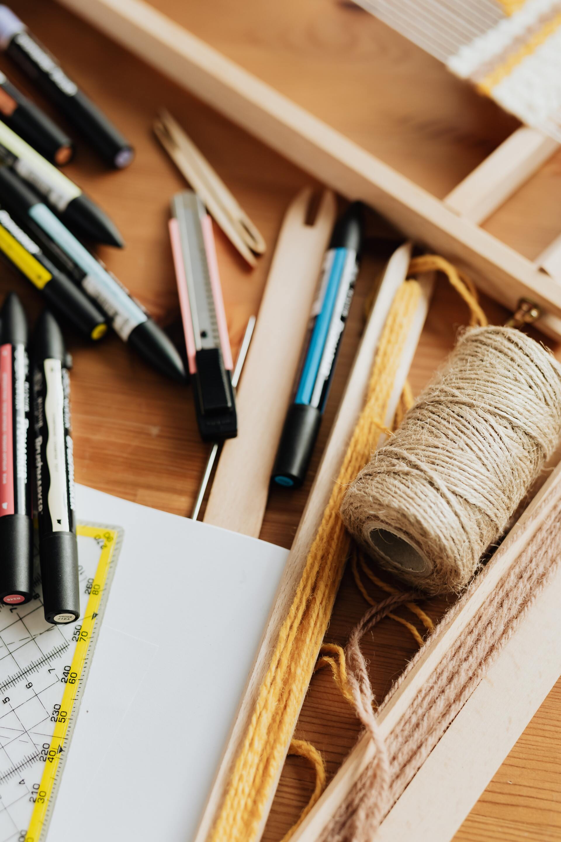 A wooden table with a spool of yarn and a bunch of pens