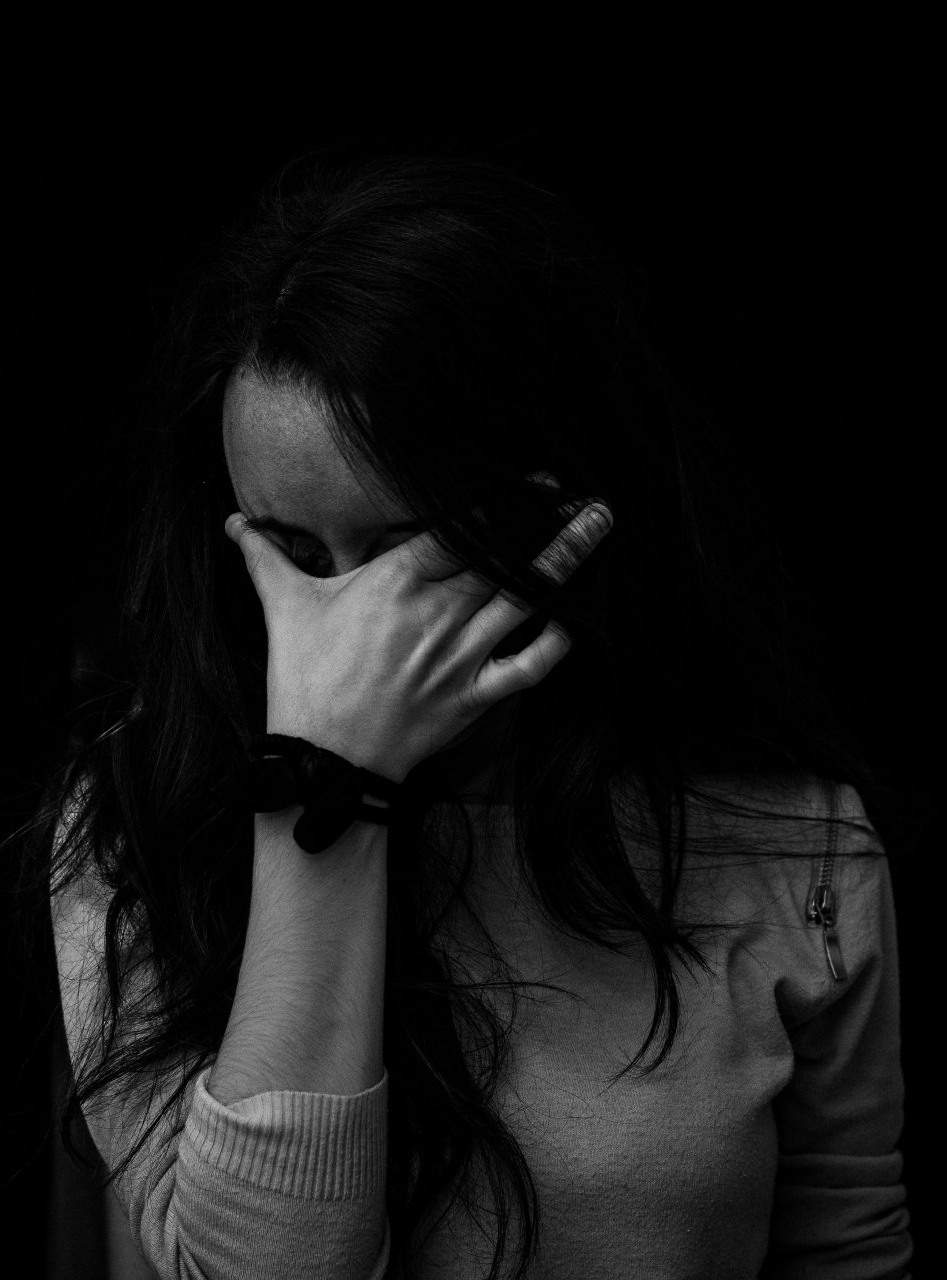 A woman is covering her face with her hand in a black and white photo.