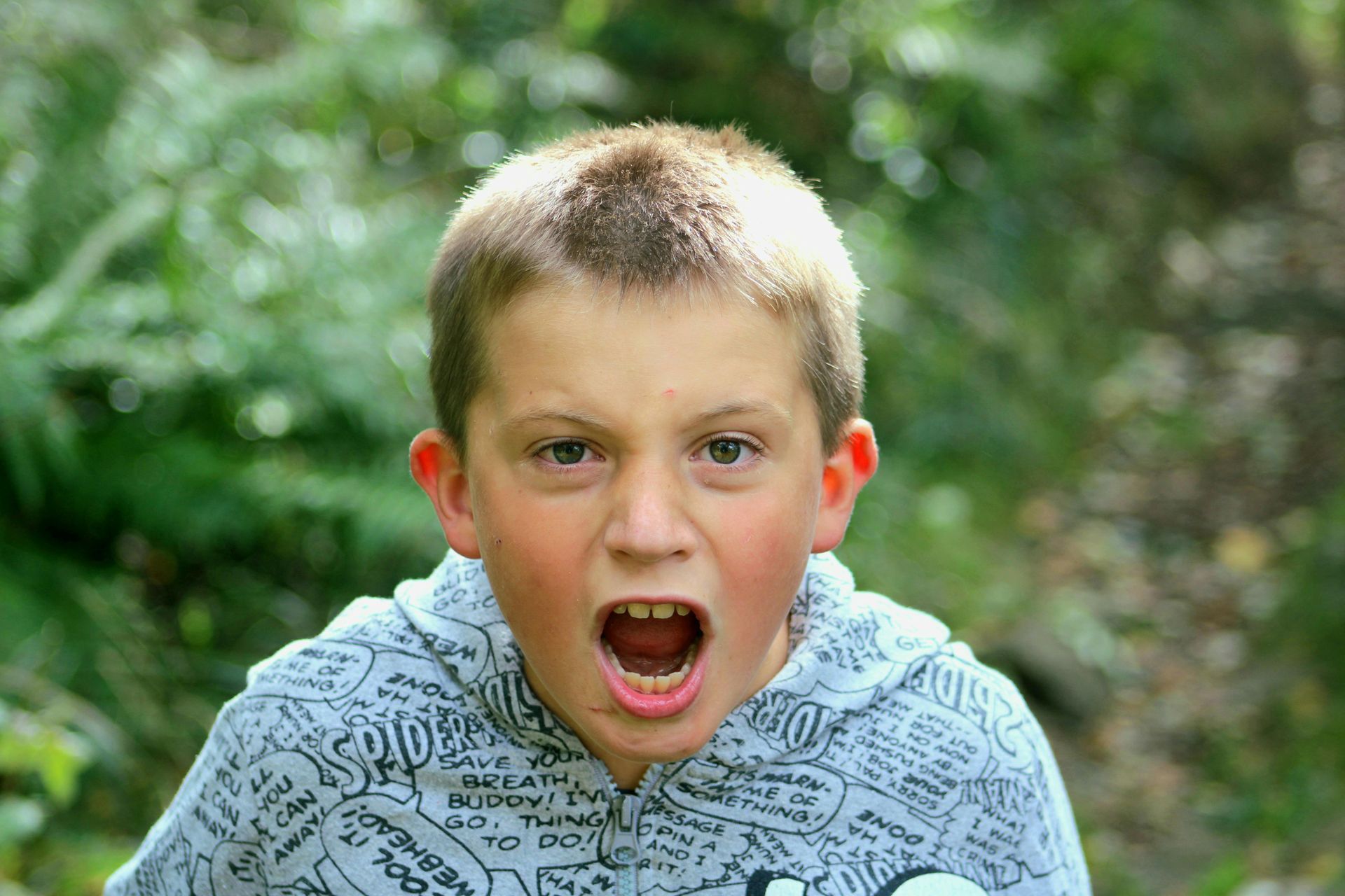A young boy is making a funny face with his mouth open.