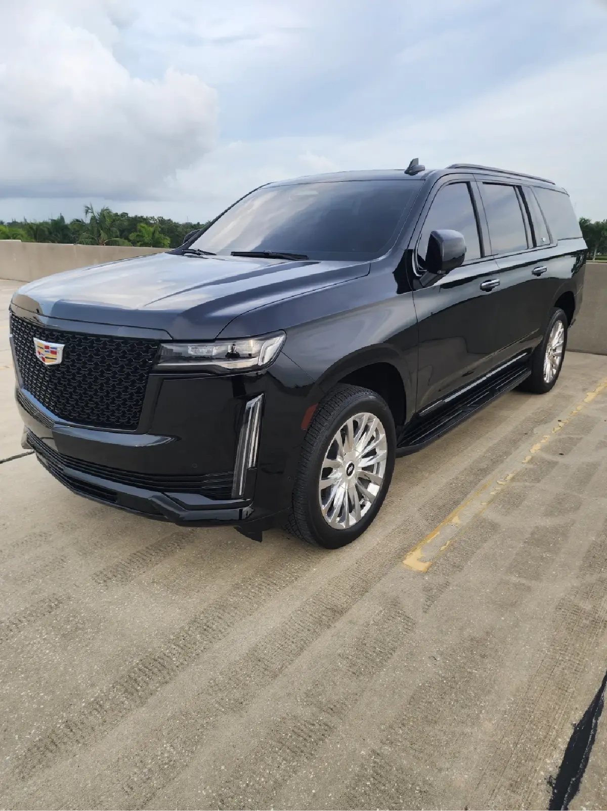 A black cadillac escalade is parked in a parking lot.