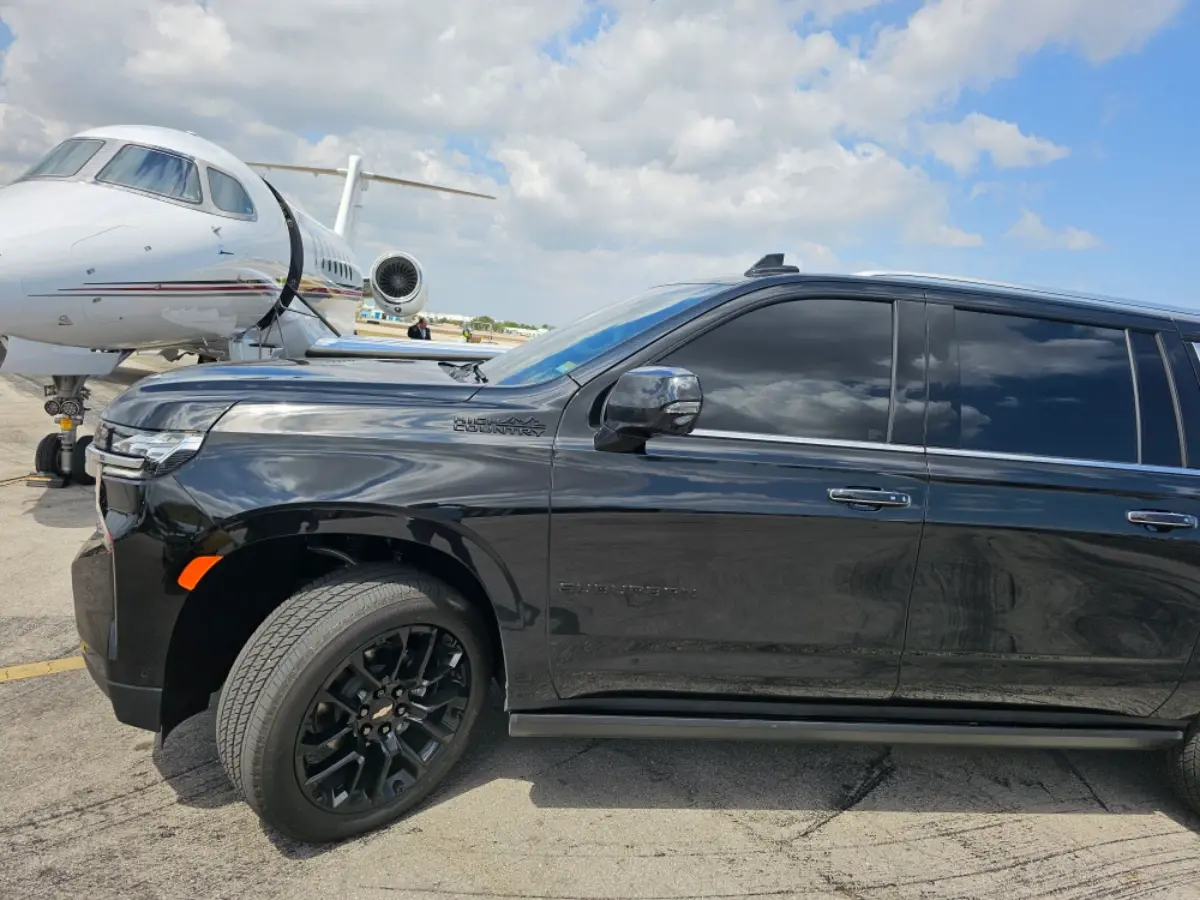 A black suv is parked in front of a private jet.