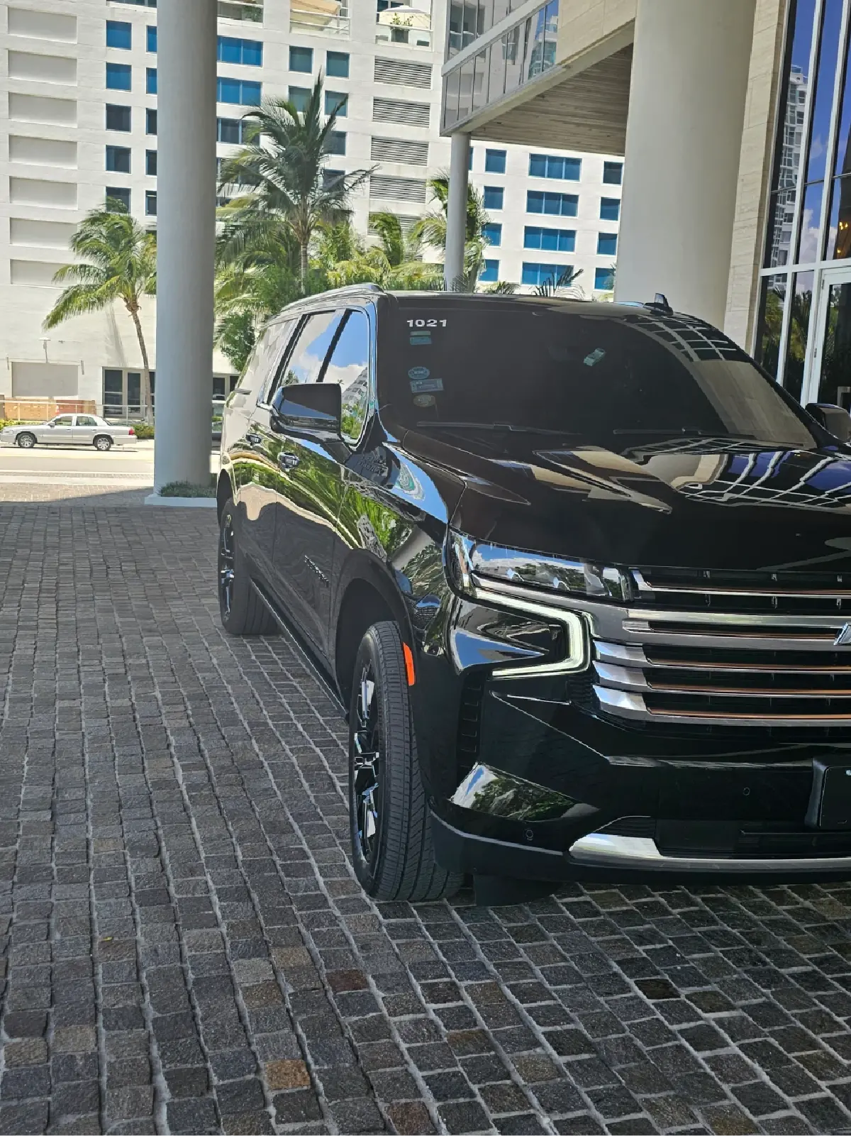 A black suv is parked on a brick driveway in front of a building.