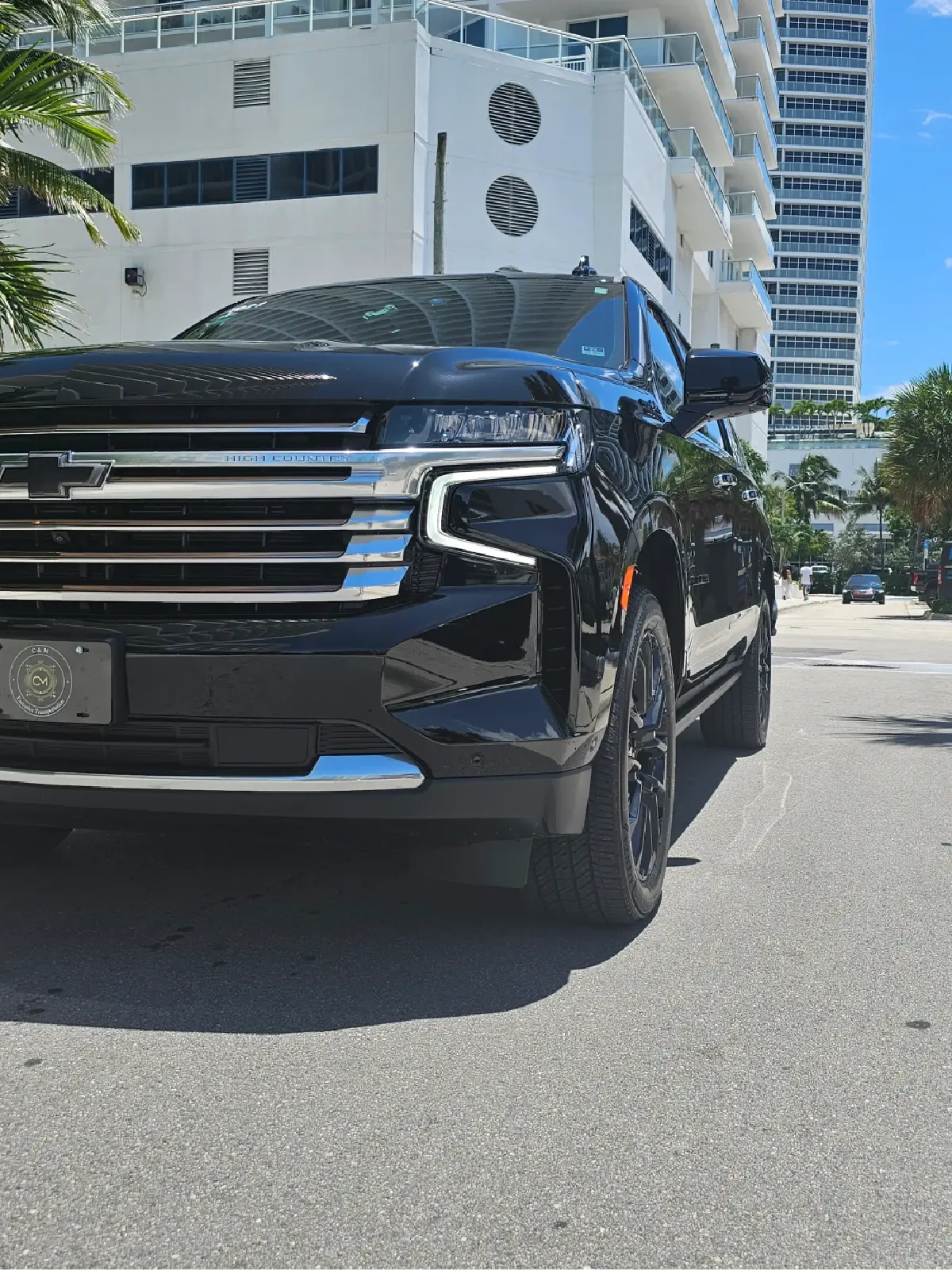 A black suv is parked on the side of the road in front of a building.