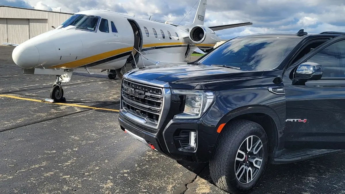 A black truck is parked in front of a private jet.