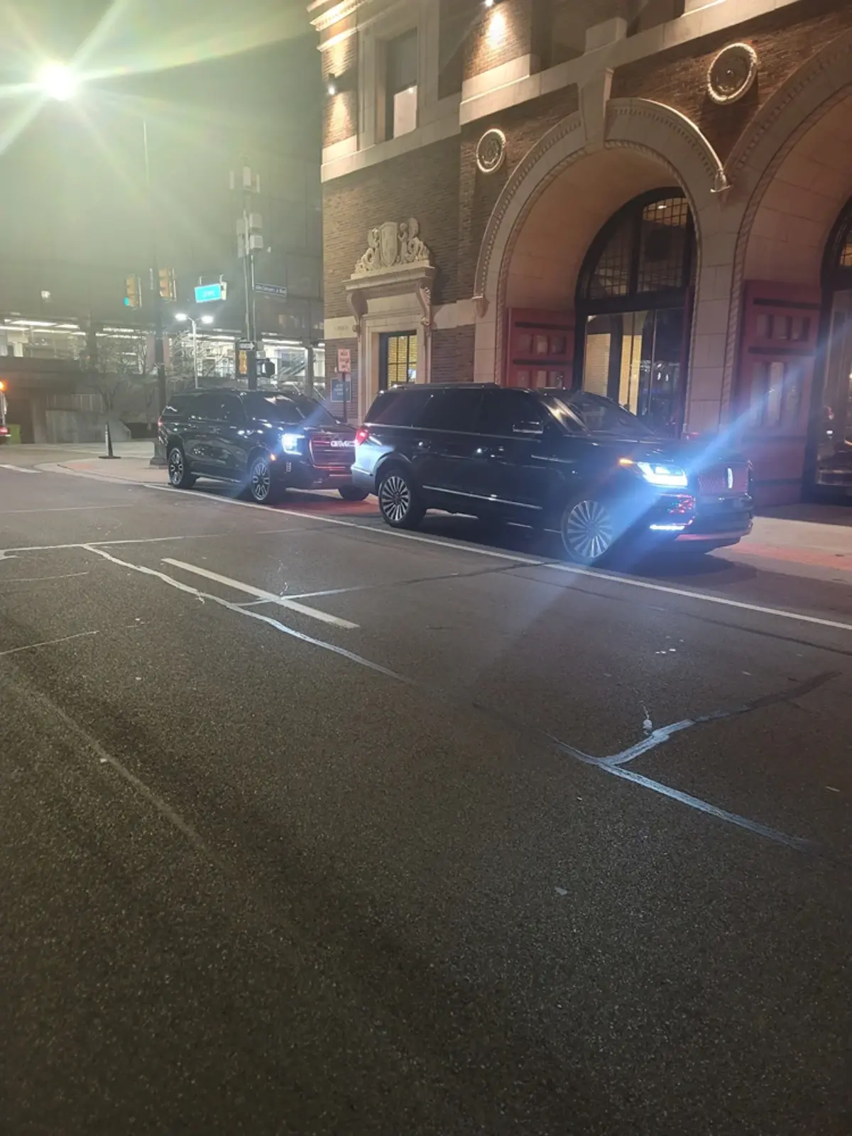 A row of cars are parked in front of a building at night