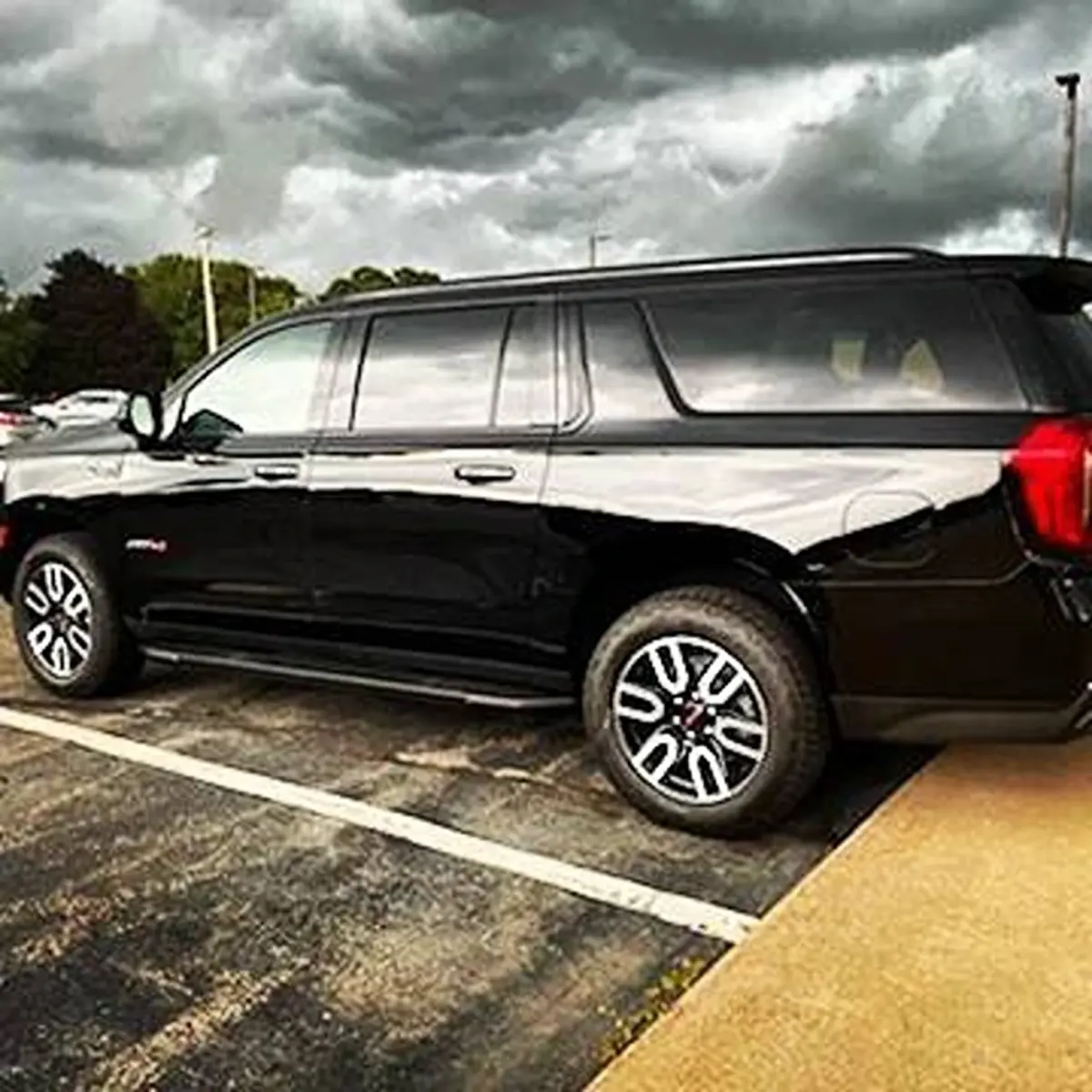 A black suv is parked in a parking lot on a cloudy day.