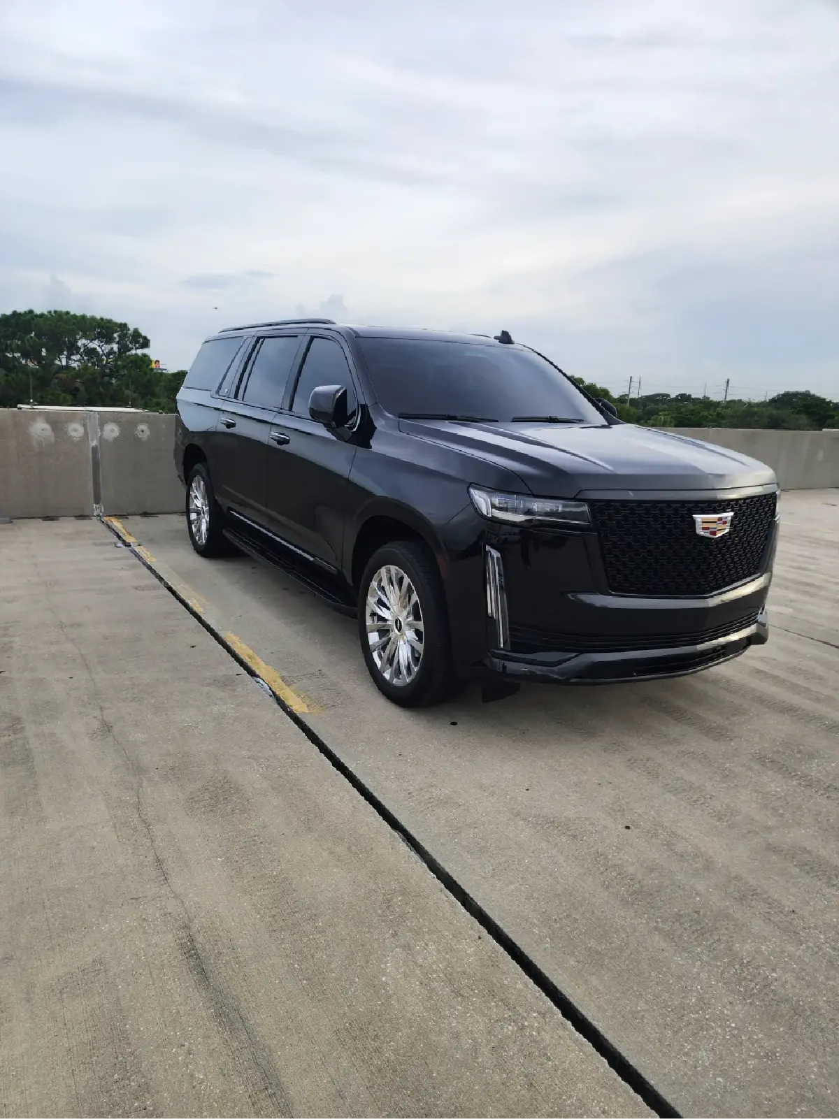 A black cadillac escalade is parked in a parking lot.