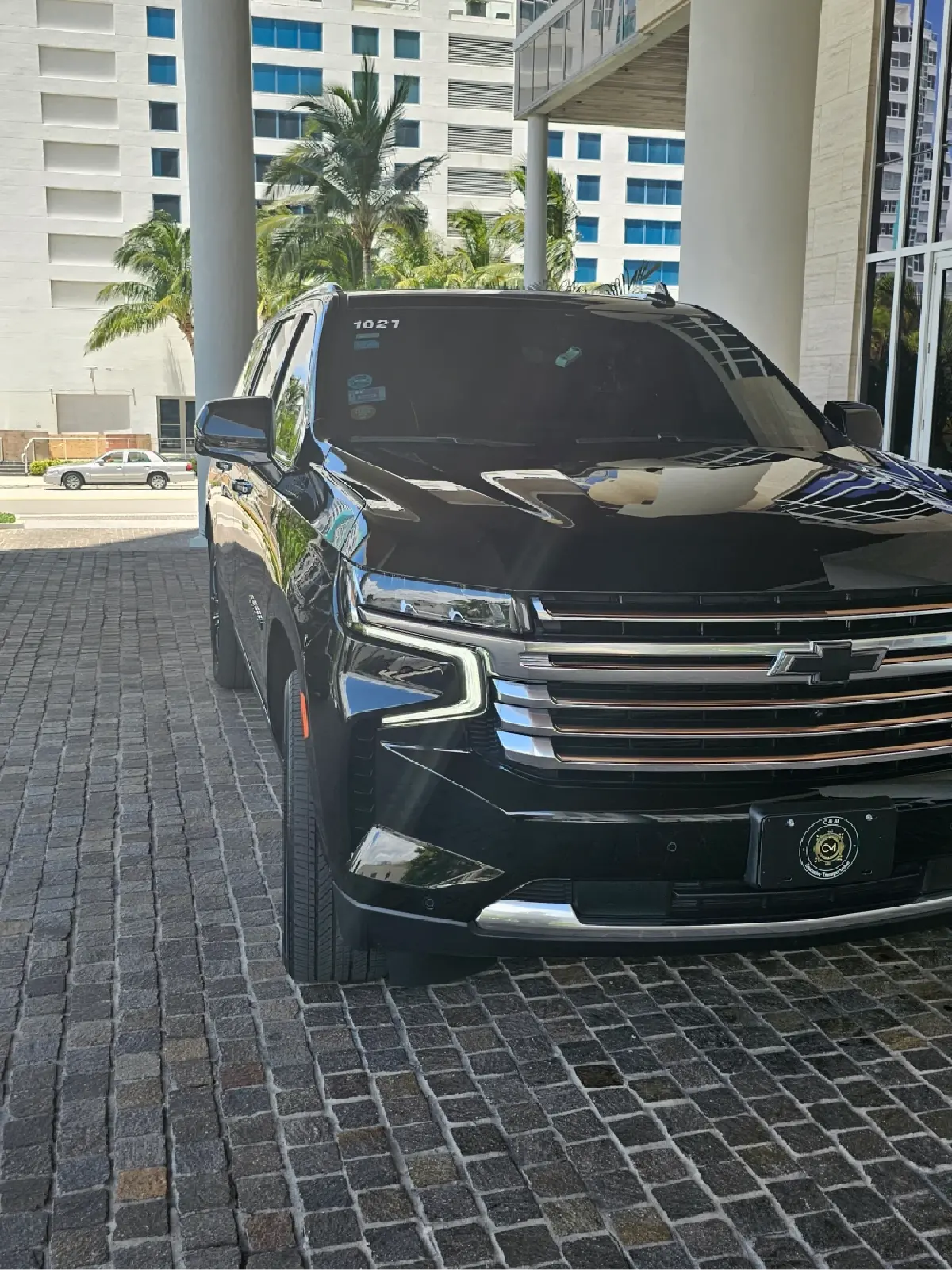 A black suv is parked on a brick driveway in front of a building.
