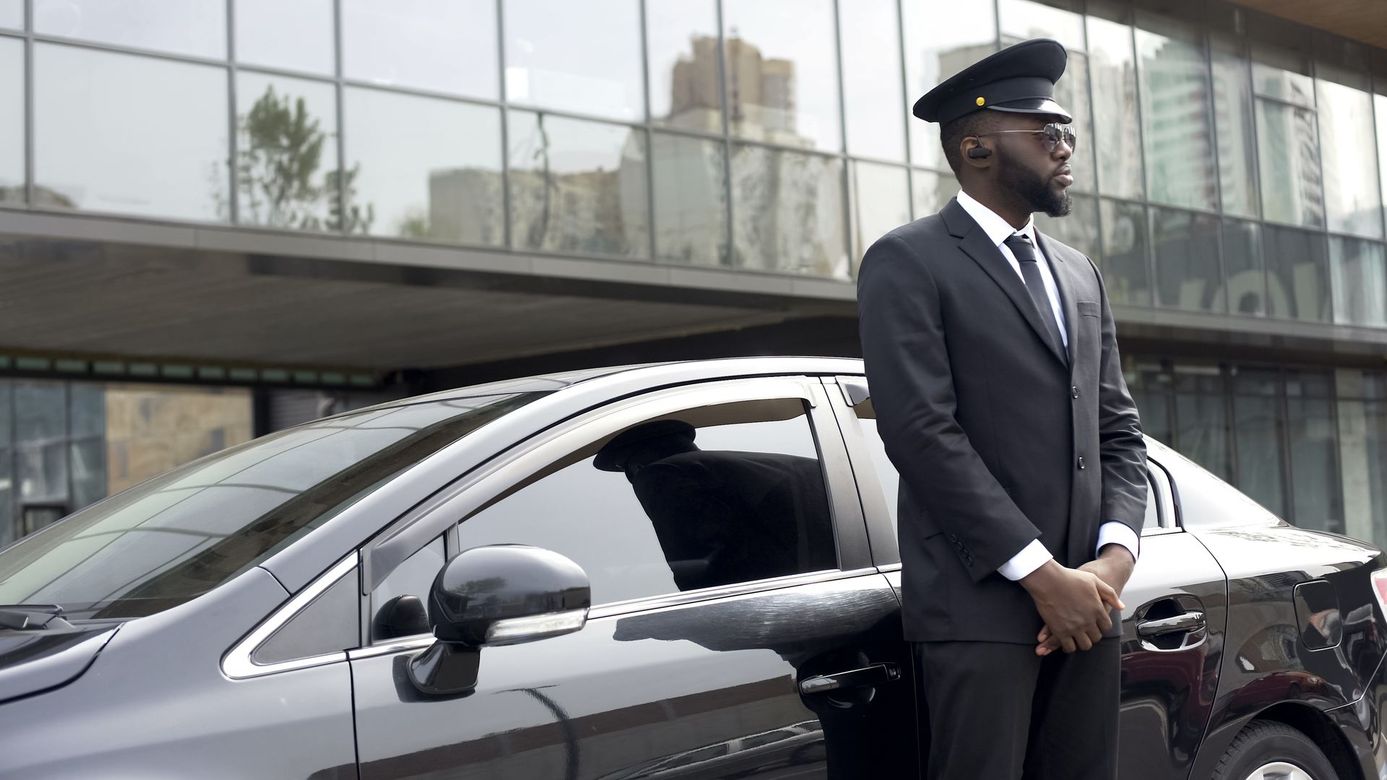 A man in a suit and tie is standing next to a car.