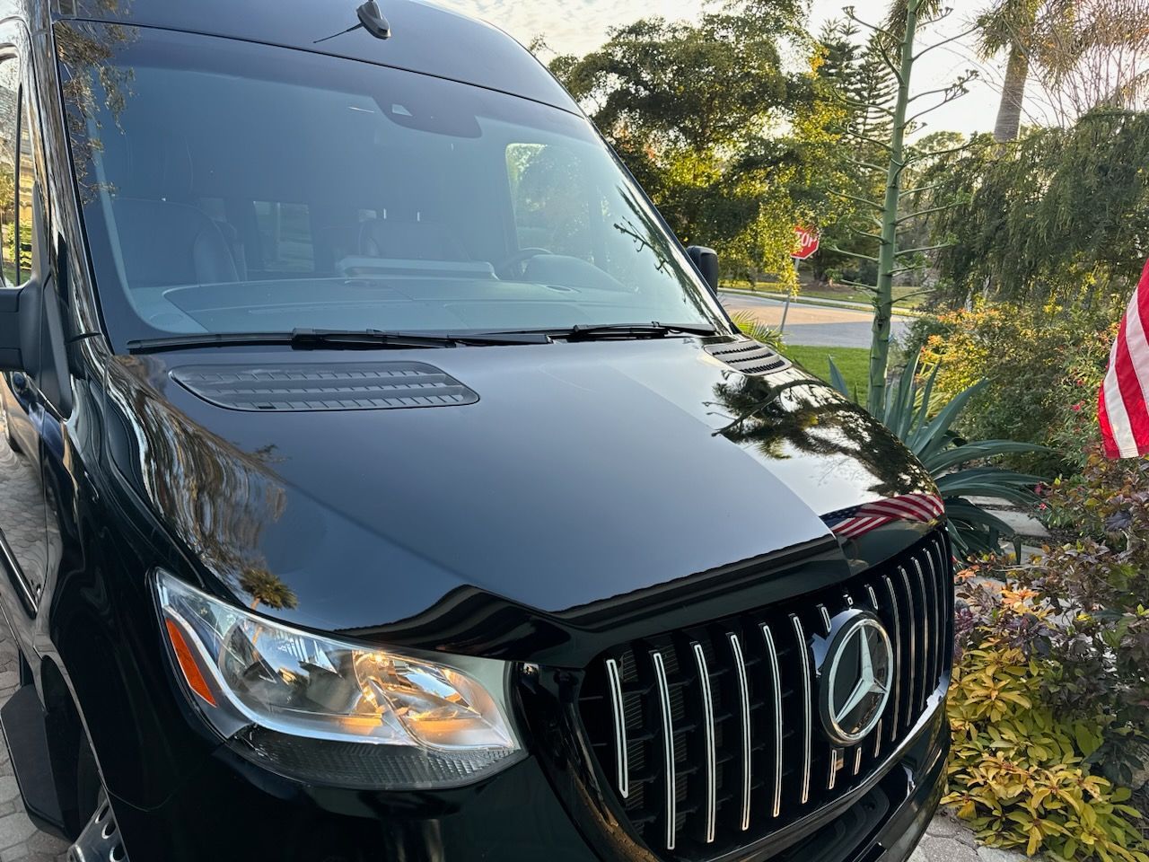 A black mercedes sprinter van is parked on the side of the road.