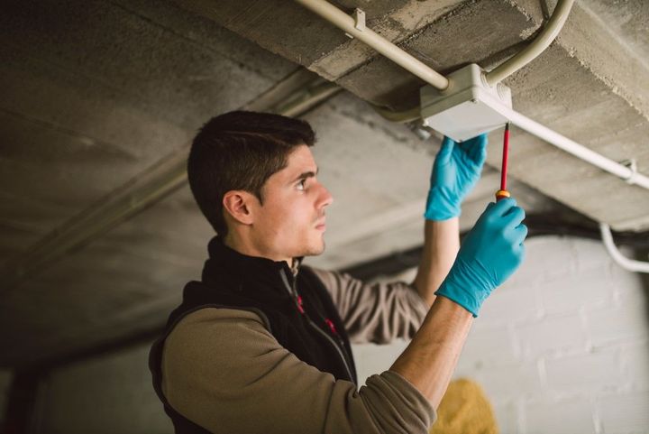 An image of electrician installing a junction box with conduit in a basement.