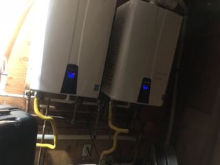 Two water heaters are sitting next to each other in a room.