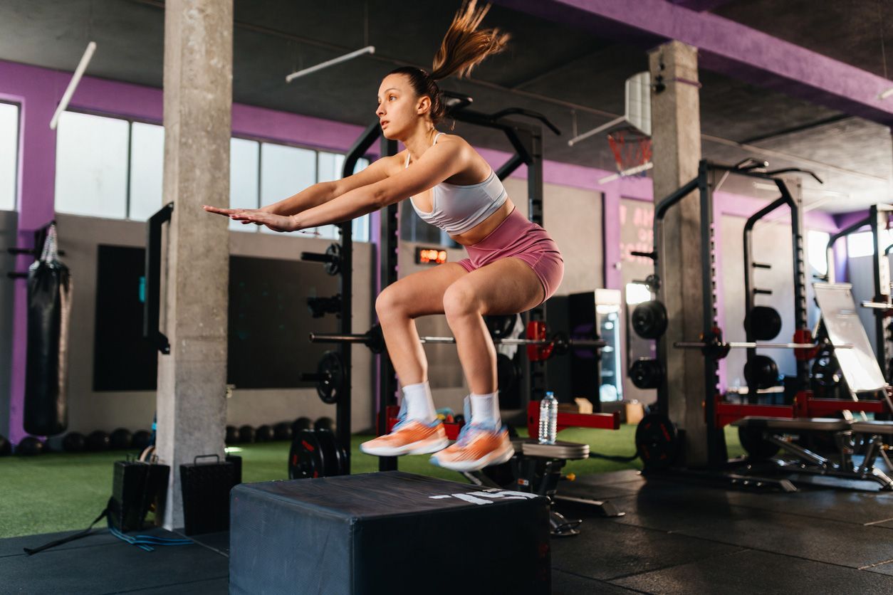 Man doing push-ups on kettlebells in a gym; gray floor, black kettlebells, and white walls.