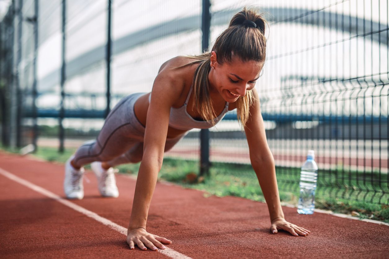 Two boys playing soccer on a green field. One in orange jersey attempts to kick the ball. The other in white defends.