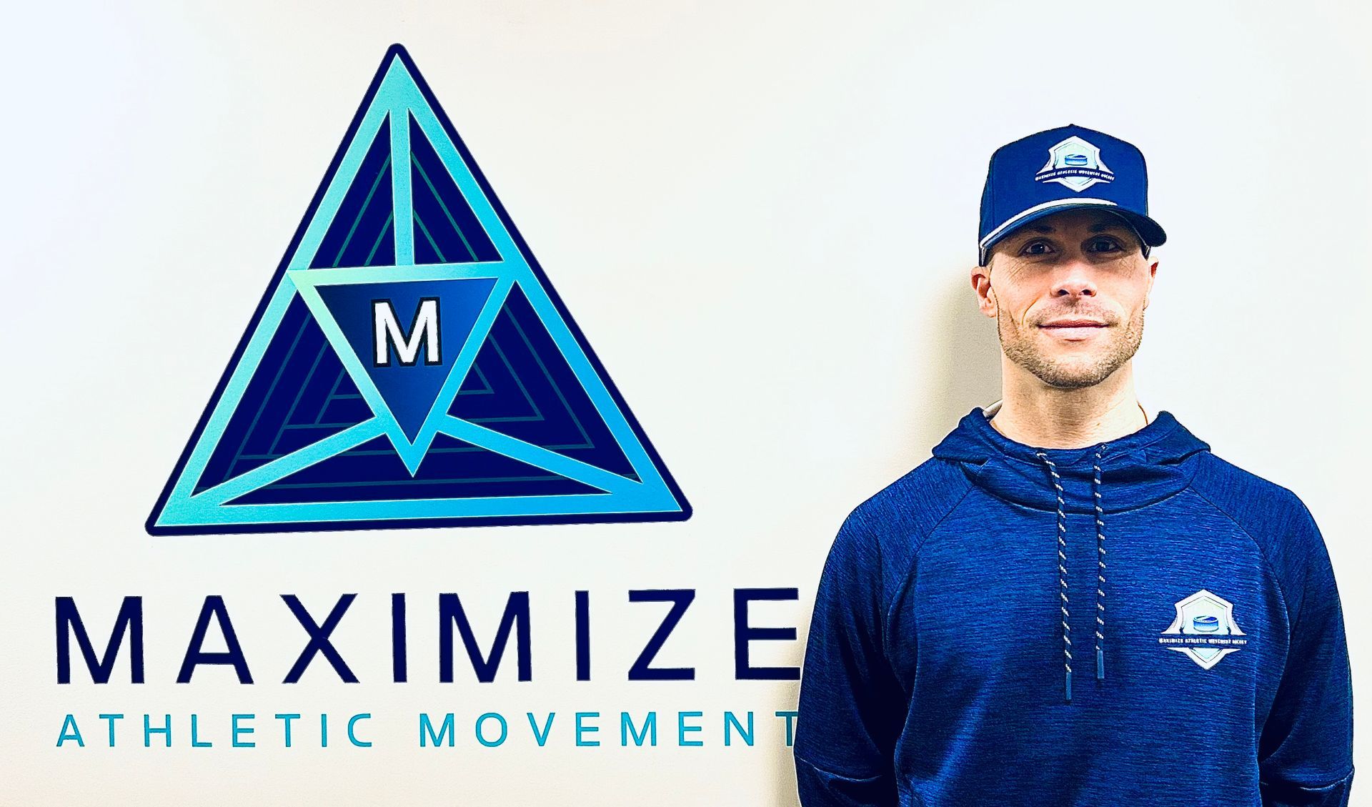 Man in blue hoodie and cap stands next to 