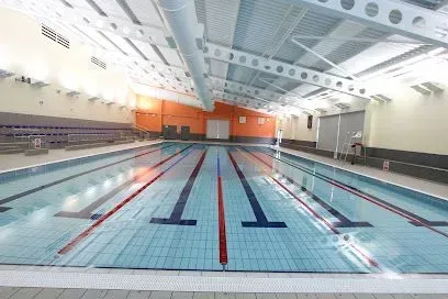 Indoor swimming pool with lanes marked by red and blue lines. Empty, well-lit, and clean.