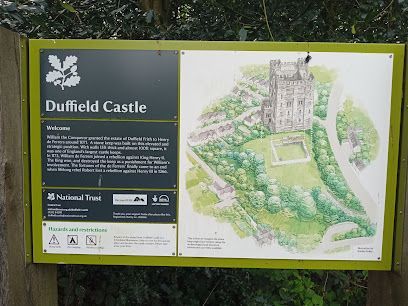 Sign for Duffield Castle with map and text on a green board, in a woodland setting.