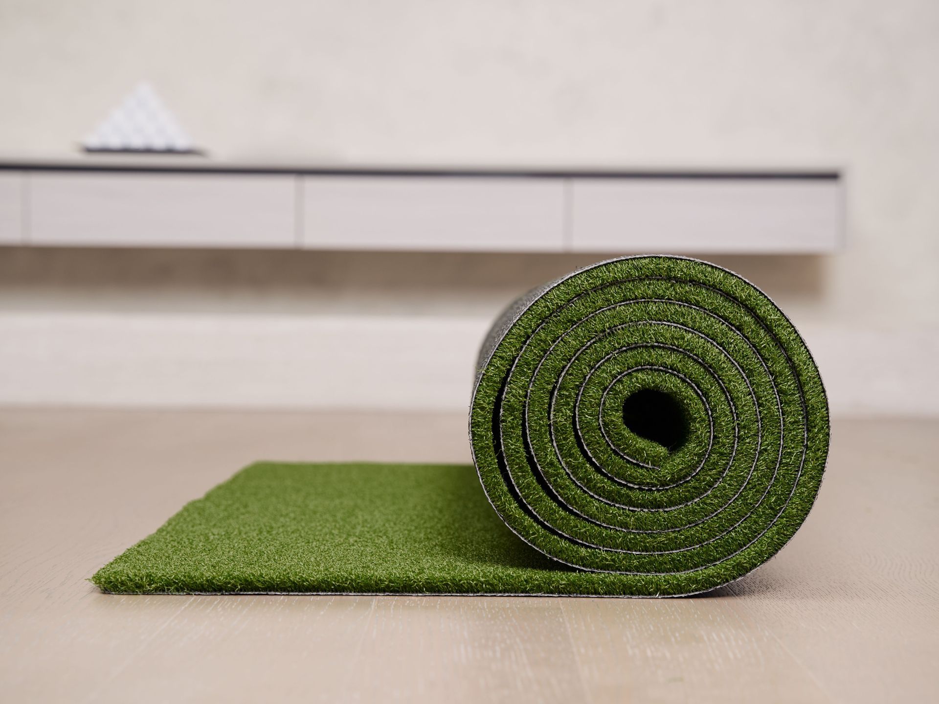 Rolled green artificial grass mat on a table, with a small black hole visible in the roll.