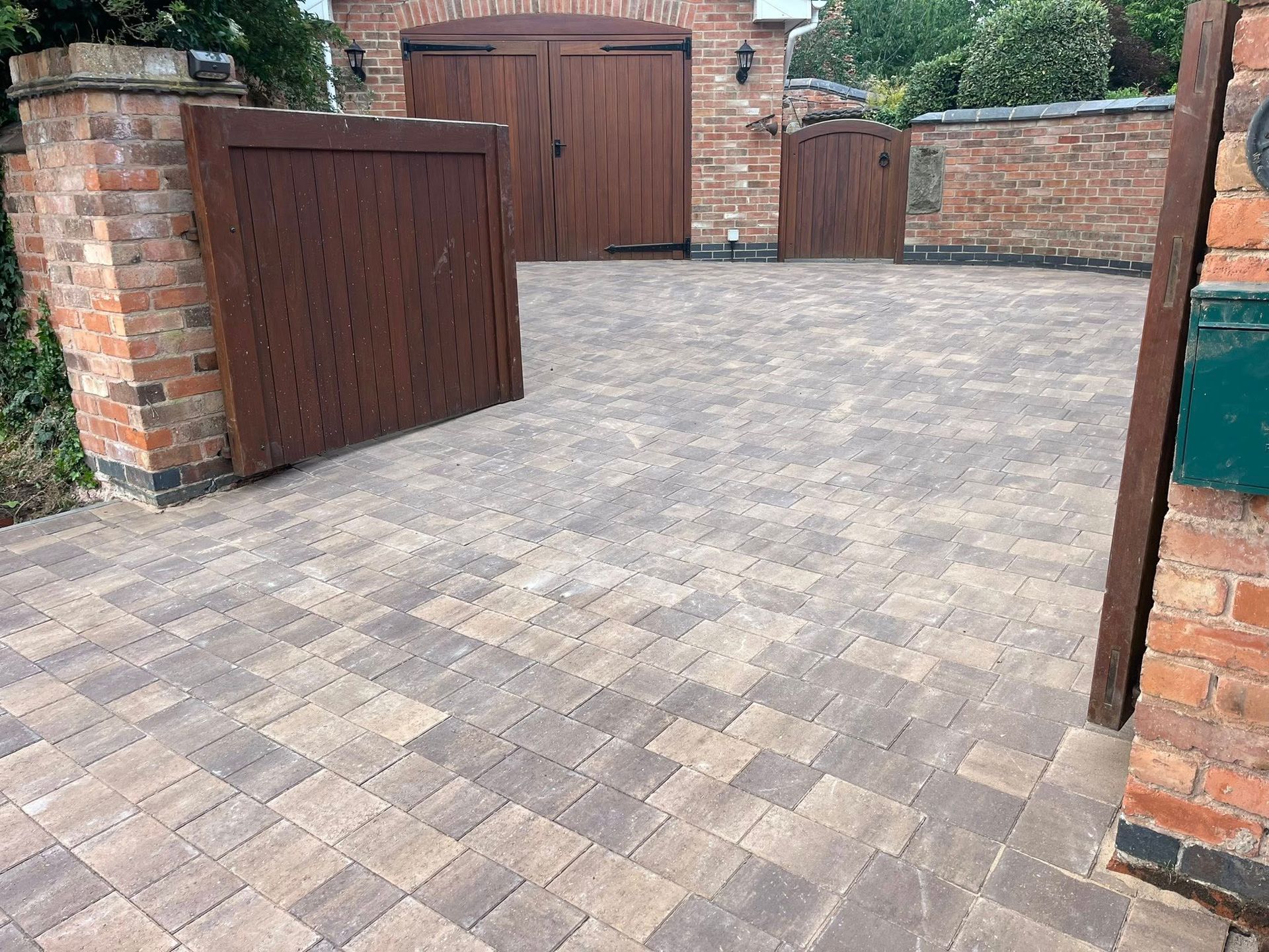 House with a gravel driveway, garage, and a stone building to the right on a sunny day.