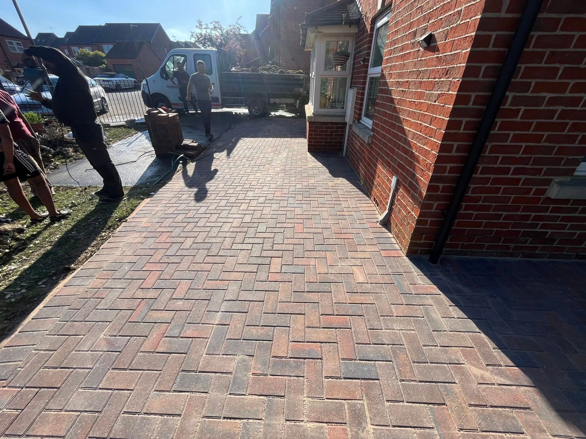 House with a gravel driveway, garage, and a stone building to the right on a sunny day.