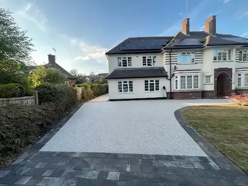 House with brown driveway and green lawn on a sunny day.