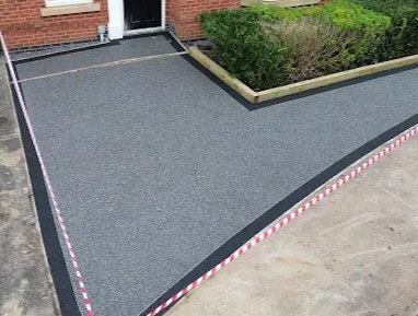 Stone buildings and resin courtyard with a red-roofed barn under a cloudy sky.