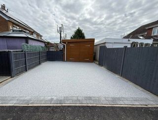 Aerial view of buildings with red tile roofs and a resin bound gravel courtyard, near a road and green space.