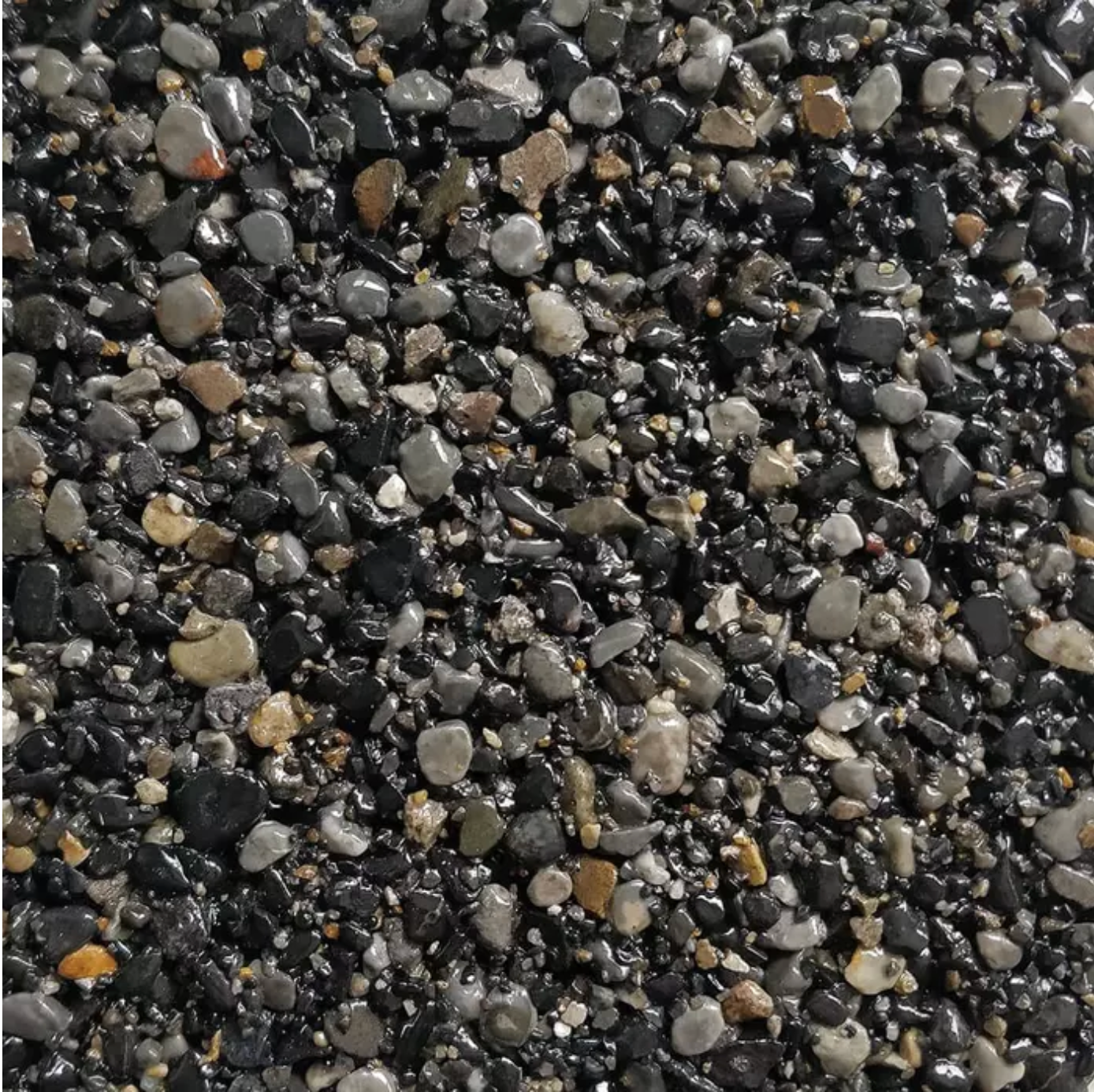 Close-up of dark, wet gravel with various sizes and shades of gray, black, and brown stones.