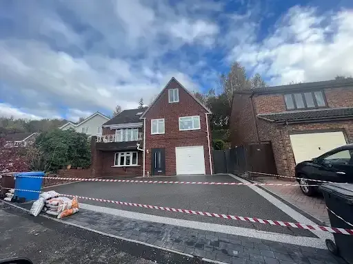 Brick house exterior with dark gray paved walkway leading to the front door.