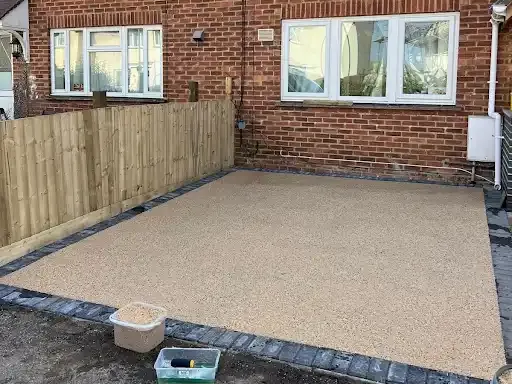 Driveway with a green trash can, a garage with a motorcycle, and a brick house.