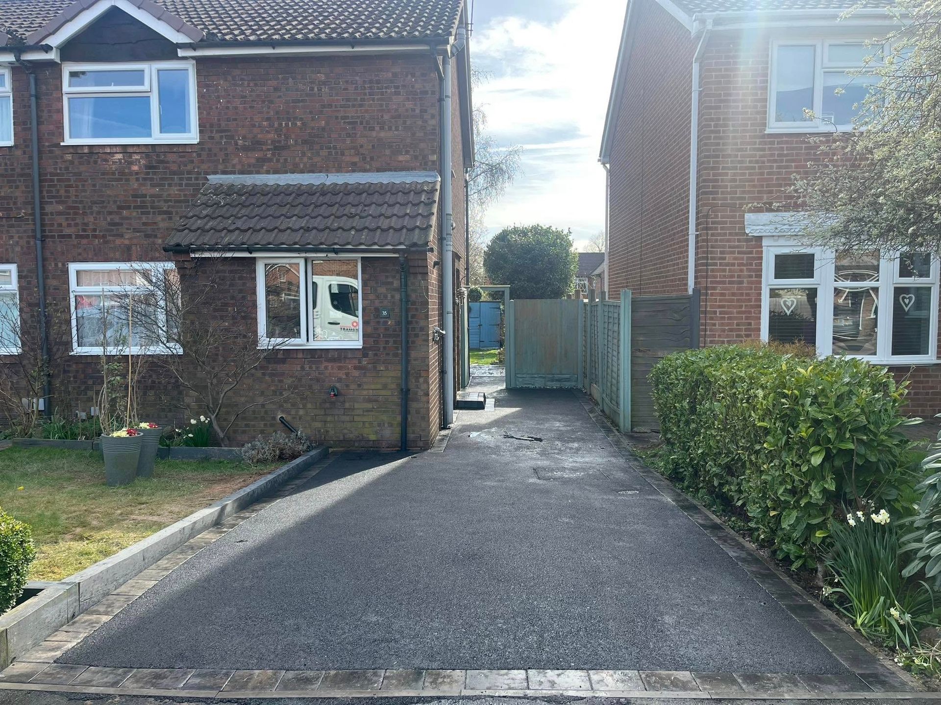 Brick house exterior with dark gray paved walkway leading to the front door.