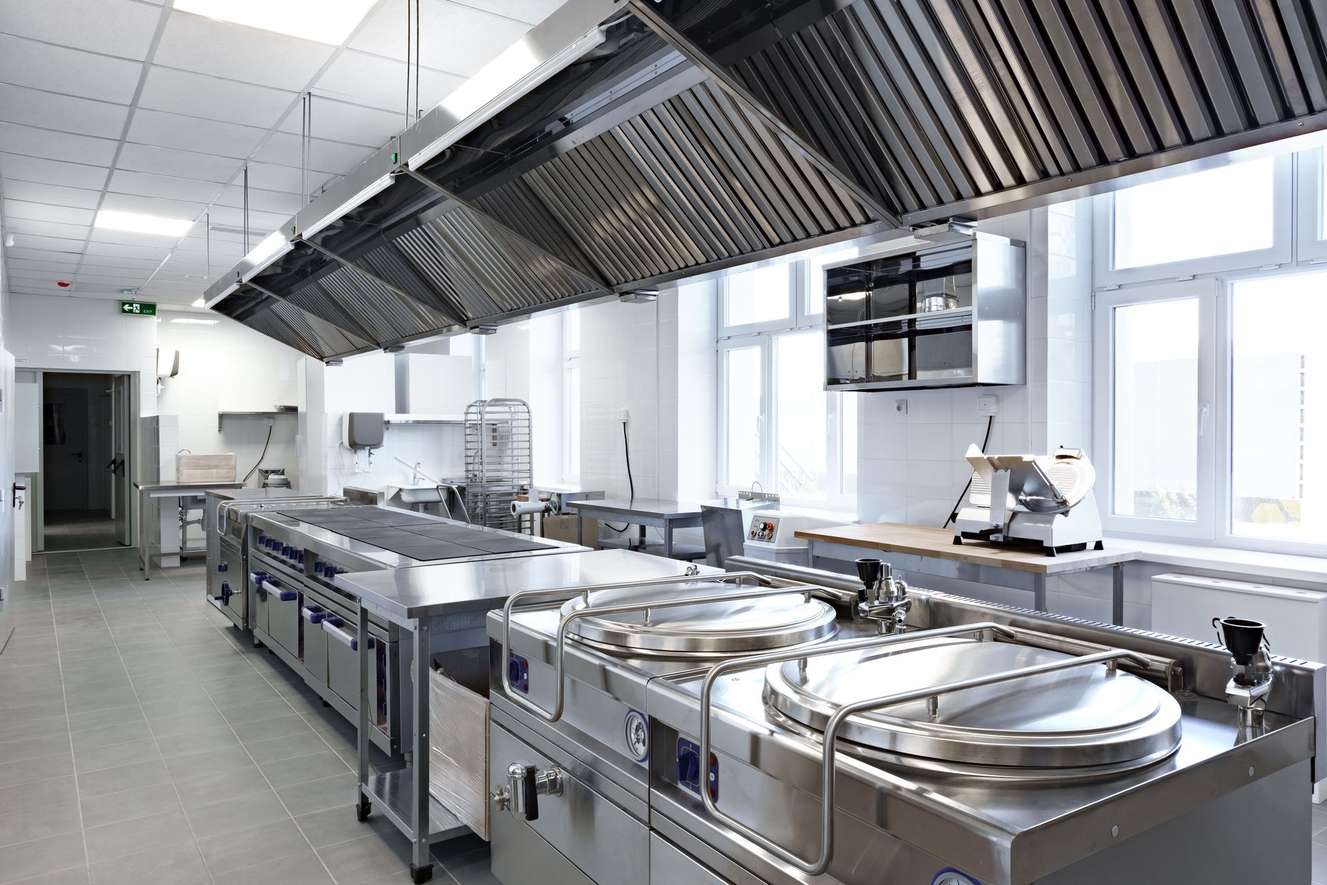 Commercial kitchen with stainless steel appliances and ventilation hoods.