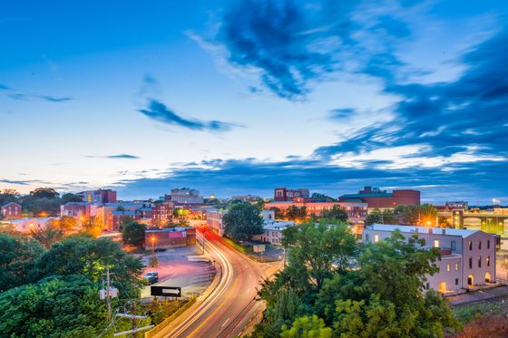 A woman is standing in front of a window talking on a cell phone.