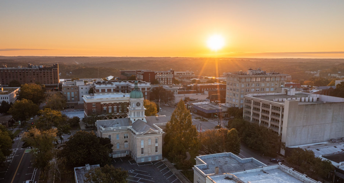 A woman is holding a baby in her arms and brushing her hair.