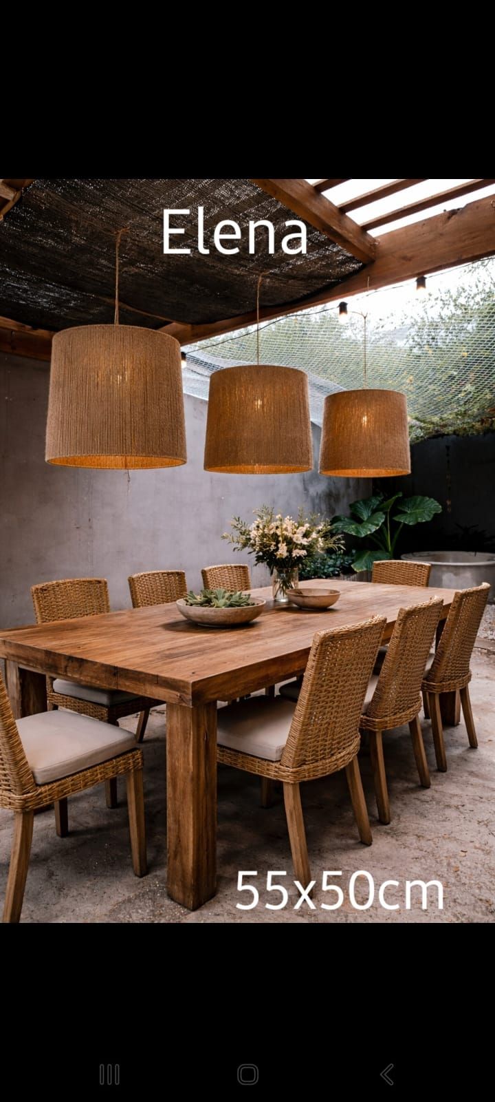 Mesa de comedor rústica con sillas de mimbre y tres lámparas colgantes de color beige en un acogedor patio cubierto.