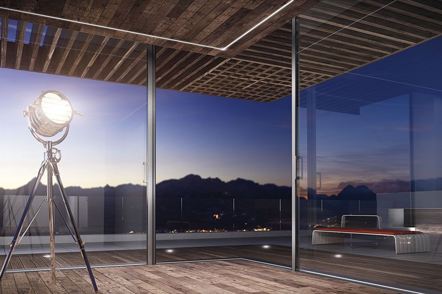 A room with a lot of windows and a lamp on a tripod.